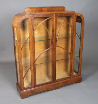 An Art Deco walnut display cabinet, the lancet bar glazed doors enclosing 2 glass shelves raised on shaped plinth base 51"h x  43"w x 12"d