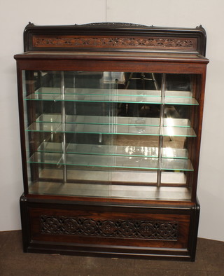 A Japanese carved mahogany and rosewood display cabinet, 20th Century, having foliate carved and pierced gallery above 2  sliding glazed doors enclosing 3 adjustable shelves, raised on  plinth base 64.5"h x 52"w x 15"w