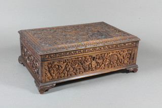 An early 20th Century Balinese carved rosewood table box, the hinged lid decorated with figures amongst Arabesques raised on scroll carved feet 5"h x 12"w x 8"d