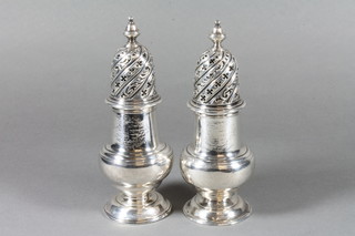 A pair of George II baluster shaped silver sugar sifters with armorial decoration, London 1744, possibly Charles Frederick  Kaudler, 13 ozs