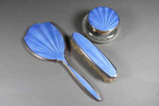 An Art Deco silver plated and blue enamelled 2 piece dressing  table set comprising hand mirror and clothes brush together with  a circular cut glass dressing table jar with blue enamelled lid