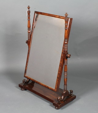 A late George IV mahogany toilet mirror having a cushion frame rectangular plate supported by ring turned columns on plinth base  with bun feet 38.5"h x 25"w x 11"d