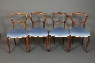 A set of 4 mid 19th Century French walnut salon chairs, having scroll carved buckle backs, stuff over seats, raised on cabriole  legs, scroll feet