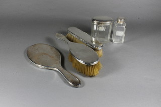 A 3 piece plain silver backed dressing table set comprising hand mirror, hair brush and clothes brush and 2 glass dressing table  jars