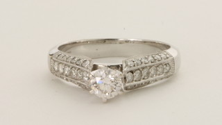An 18ct white gold dress ring set a solitaire diamond and with diamonds to the shoulders