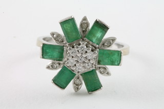 An 18ct white gold floral cluster dress ring set emeralds and diamonds