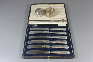 A set of 6 silver handled tea knives, a silver handled paper knife,  napkin ring, circular dressing table jar with silver lid