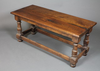 An oak low table in the 18th Century style with moulded  rectangular top on baluster supports united by stretchers, bun  feet, 22"h x 50"w x 22"d