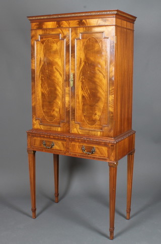 A Georgian style mahogany cocktail cabinet, the upper section  with moulded cornice, fitted shelves enclosed by arch panelled  doors, the base fitted 2 long drawers raised on square tapering  supports 66.5"h x 30"w x 15"d