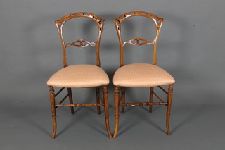 A pair of Victorian pierced mahogany balloon back bedroom  chairs with carved mid rails and upholstered seats, raised on  turned supports