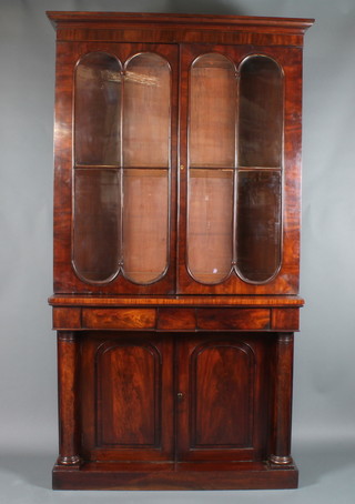 A Victorian mahogany bookcase on cabinet the upper section  with moulded cornice, the interior fitted adjustable shelves  enclosed by glazed panelled doors, the base fitted 2 long drawers  above a double cupboard with columns to the sides 90"h x 47"w  x 18"d