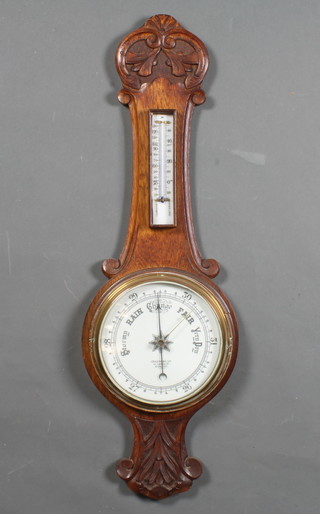 An aneroid barometer and thermometer with enamelled dial contained in a carved wheel case