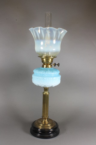 A Victorian opaque blue glass oil lamp reservoir on a reeded  brass column and with a "vaseline" glass shade