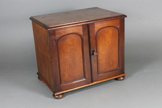 A Victorian mahogany table cabinet, having a pair of panelled cupboard doors enclosing an arrangement of 7 small drawers,  raised on flattened bun feet 10"h x 11.5"w x 8"d