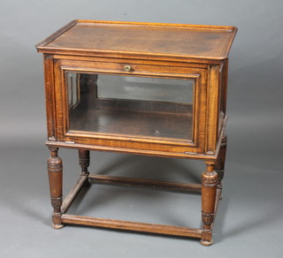 An early 20th Century oak serving table, having a rectangular moulded top above a glazed tier with end doors, raised on turned  supports united by stretchers 30"h x 27.5"h x 19"d