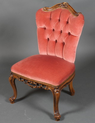 A Victorian style walnut show frame nursing chair upholstered in  pink material on cabriole supports