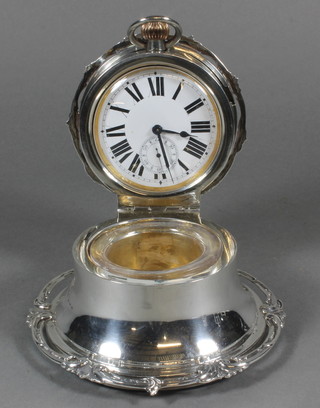 A handsome Edwardian circular desk inkwell, the engraved and pierced hinged silver lid incorporating an 8 day Goliath pocket  watch with enamelled dial and Arabic numerals, complete with  glass inkwell, Birmingham 1907 4.5"   ILLUSTRATED
