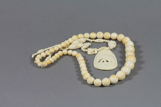 A string of ivory beads and a carved ivory pendant hung on a pierced ivory necklet