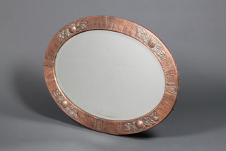 An Art Nouveau style oval bevelled plate wall mirror contained in a planished copper frame 