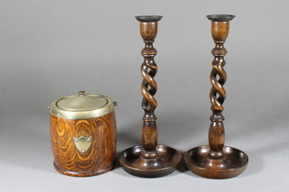 A circular turned oak biscuit barrel with silver plated mounts 5" and a pair of oak spiral turned candlesticks with metal sconces 13"