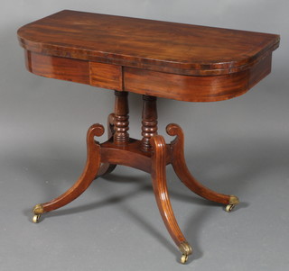 A Regency mahogany D shaped tea table, raised on 2 turned  columns with triform base and having splayed legs ending in  brass caps and casters 28"h x 36"w x 18"d