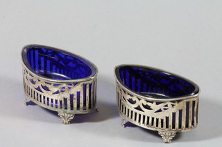 A pair of oval Adam style pierced silver table salts with blue glass liners, Birmingham 1918, maker W H Lyde