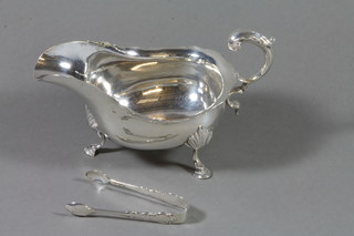 An Edwardian silver sauce boat with wavy border, raised on hoof feet, Sheffield 1900 together with a pair of silver sugar tongs, 9ozs