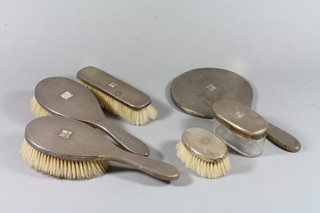 A silver backed 4 piece dressing table set comprising pair of hair brushes, hand mirror and clothes brush London 1923, matching oval dressing table jar with silver lid together with an oval silver backed military hair brush London 1943