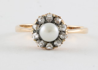 A gold dress ring set a pearl surrounded by diamonds