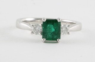 An 18ct white gold dress ring set a rectangular cut emerald approx 0.98ct supported by 2 diamonds approx. 0.24ct