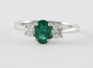 An 18ct white gold dress ring set an oval emerald approx. 0.76ct surrounded by diamonds, approx. 0.36ct