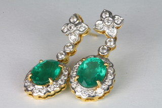 A pair of yellow gold drop earrings set emeralds surrounded by diamonds ILLUSTRATED