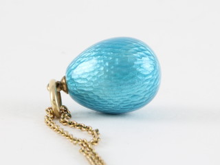 A blue enamelled egg shaped pendant hung on a gold chain