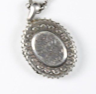 An oval engraved silver locket hung on a chain