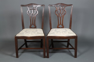 A pair of Georgian carved mahogany dining chairs with serpentine drop in seats on square chamfered legs 