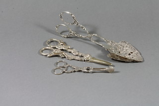A pair of white metal sugar nips, a pair of silver plated grape scissors and a pair of white metal sandwich servers