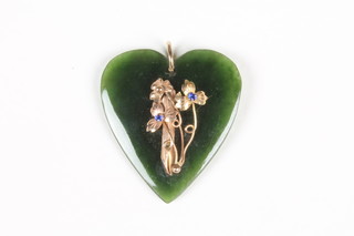 A carved nephrite heart shaped pendant set with gilt flowers