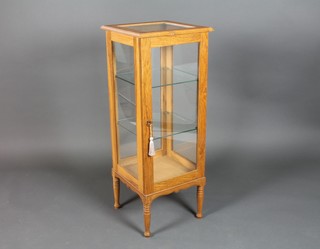An oak glazed pedestal display cabinet, the interior fitted shelves enclosed by panelled doors, raised on turned supports 41"h x 15 1/2"w x 16"d 