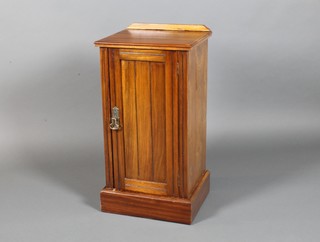 An Edwardian walnut bedside cabinet enclosed by a panelled door, raised on a platform base 29 1/2" x 15"w x 13"d 