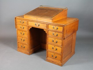 A Victorian oak kneehole pedestal desk, the upper section fitted a slope with brown skiver above 1 long and 10 short drawers, having drop flaps to the side and incorporating a bookcase to the reverse 36"h x 60"w x 24"d 