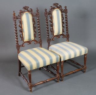 A pair of Victorian oak Carolean style high back chairs with upholstered seats and backs, spiral turned columns to the sides, raised on turned and block supports