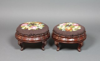 A pair of Victorian carved mahogany circular footstools, the seats upholstered in Berlin woolwork raised on cabriole supports 12 1/2" diam.