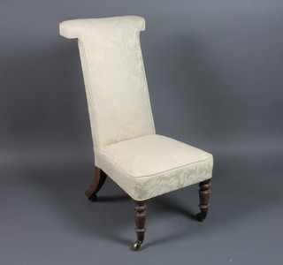 A Victorian rosewood prie-dieu chair upholstered in white material, raised on turned supports with brass caps and casters 