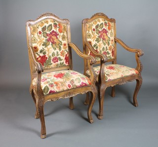 A pair of Italian style carved walnut open arm chairs with upholstered seats and backs, raised on cabriole supports 