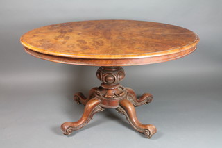 A Victorian figured walnut oval snap top Supper table raised on a turned column tripod base 62"w x 42"d