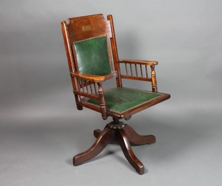 An Edwardian oak office swivel chair, the seat and back upholstered in green leather, with brass plaque reading Presented to Mr G Gray by the Boys of Handle College 1897-1910