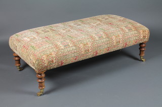 A Victorian style rectangular oak stool upholstered in tapestry material, raised on turned supports ending in brass caps and casters 13"h x 47"w x 24"d 
