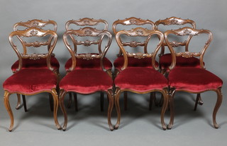 A set of 8 Victorian carved rosewood buckle back dining chairs with carved mid rails, the upholstered seats of serpentine outline, raised on cabriole legs