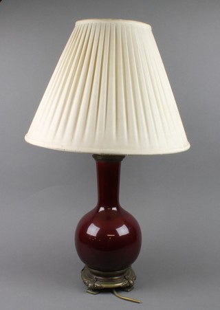 A red glazed baluster vase with elongated neck, converted to electricity on a gilt metal base
