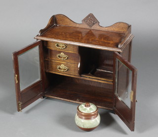 An Edwardian oak smoker's cabinet, the top with three-quarter gallery, the interior fitted 3 drawers above a recess and having a pottery tobacco jar, enclosed by bevelled glazed panelled doors 16 1/2"h x 17"w x 8"d